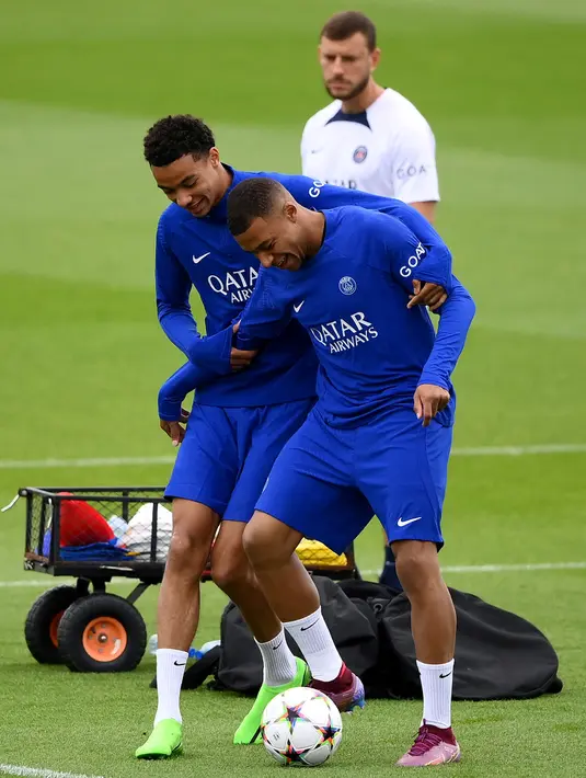 Pemain Paris Saint-Germain Kylian Mbappe (kiri) tertawa bersama Hugo Ekitike saat sesi latihan di tempat latihan klub di Saint-Germain-en-Laye, Prancis, Selasa (13/9/2022). Paris Saint-Germain (PSG) akan melawan Maccabi Haifa pada pertandingan sepak bola putaran pertama Grup H Liga Champions. (FRANCK FIFE/AFP)