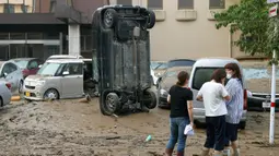 Sebuah mobil berdiri secara vertikal di jalan berlumpur setelah tersapu banjir di Hitoyoshi, prefektur Kumamoto, barat daya Jepang, Minggu (5/7/2020). Hujan deras di wilayah Kumamoto memicu banjir dan tanah longsor pada Sabtu dan menyebabkan banyak warga yang terisolasi. (Kyodo News via AP)