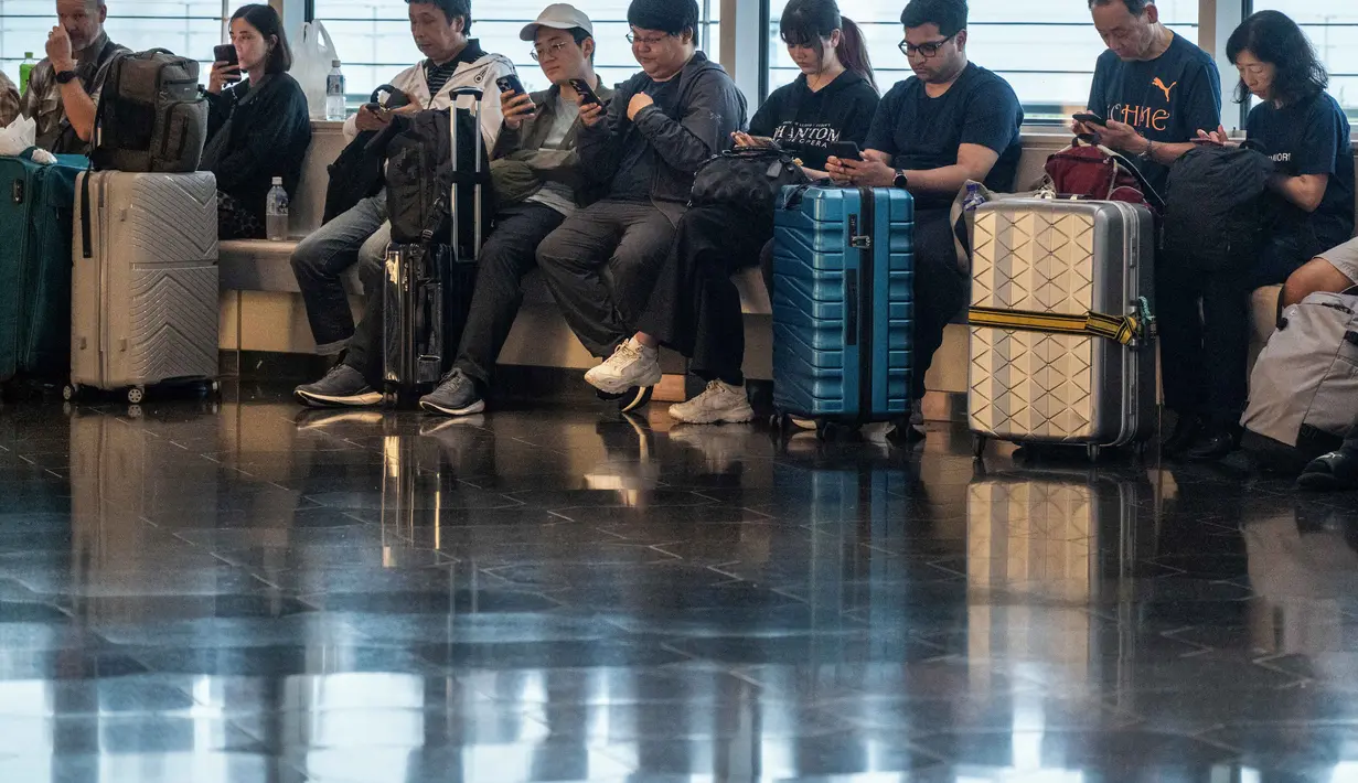 Penumpang menunggu di Terminal Internasional Bandara Haneda setelah penerbangan dibatalkan atau ditunda karena badai tropis Jangmi di Tokyo, Jepang, Rabu 3 Juni 2026. (Andrew CAALLERO-REYNOLDS/AFP)
