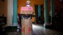 Pensiunan perawat, Feridia Rojas (82) bersiap mengenakan kotak kardus berbentuk rumah untuk melindungi dirinya dari penyebaran Covid-19 di Havana, Kuba, 8 Juli 2020. Pakaian pelindung kardus itu dipakai Rojas untuk melakukan aktivitas di luar rumah sehari-hari seperti berbelanja. (AP/Ramon Espinosa)