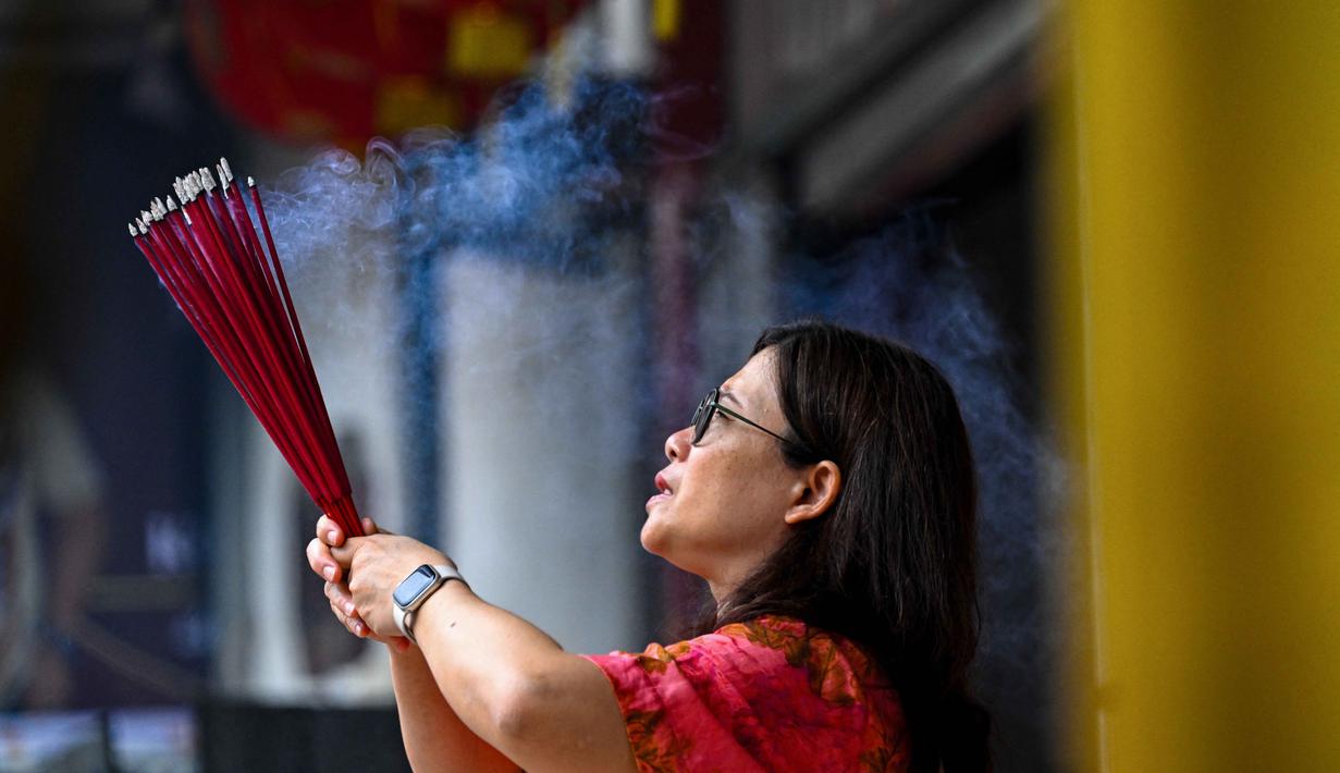 Ketua Yayasan Vihara Dharma Bakti Banda Aceh, Yuswar, pada Selasa 17 Februari 2026, memastikan perayaan Tahun Baru Imlek 2577 Kongzili atau 2026 Masehi tanpa adanya pertunjukan barongsai. Tampak dalam foto, seorang wanita membakar dupa saat berdoa di sebuah kuil pada hari pertama Tahun Baru Imlek 2577 Kongzili di Banda Aceh, Provinsi Aceh, pada Selasa 17 Februari 2026. (CHAIDEER MAHYUDDIN/AFP)