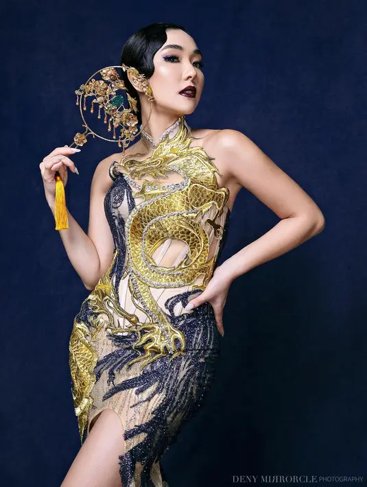 Penampilan luar biasa Gisella Anastasia mengenakan cheongsam bernuansa biru dan kuning. Cheongsam ini dipenuhi bordir berbentuk naga yang megah, ditambah makeup bold, tatanan rambut wet look, dan berbagai aksesori yang dikenakan Gisel di foto ini. Foto: Instagram.