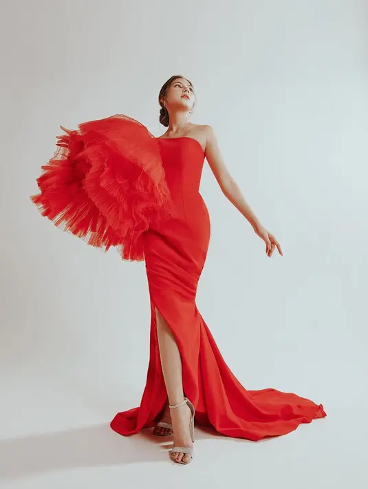 Penampilan luar bisa Jessica Mila dibalut gaun megah berwarna merah. Off-the-shoulder dress ini memiliki detail ruffles yang dramatis di salah satu sisi, high-slit, dan train yang menjuntai ke lantai. Foto: Instagram.
