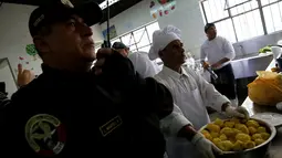 Seorang petugas berdiri di samping narapidana yang tengah membuat masakan dalam kompetisi kuliner 'INPE Mistura 2016' di penjara perempuan Chorrillos di Lima, Peru, Rabu (7/9). Kompetisi masak antar penjara ini diadakan setiap tahun (REUTERS/Mariana Bazo)