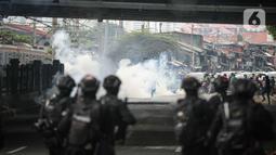 Pengunjuk rasa berlarian menghindari gas air mata yang ditembakkan oleh polisi di depan pintu gerbang gedung DPR RI, Jakarta, Senin (11/4/2022). Situasi mulai memanas akibat sejumlah pengunjuk rasa melempari petugas dengan berbagai benda lainnya. (Liputan6.com/Faizal Fanani)