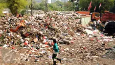 Warga melintas di dekat tumpukan sampah yang ada di Tempat Pembuangan Sampah Sementara Kalibata, Jakarta, Rabu (4/11/2015). Penumpukan sampah terkait aksi pemblokadean jalan menuju TPST Bantar Gebang. (Liputan6.com/Helmi Fithriansyah)