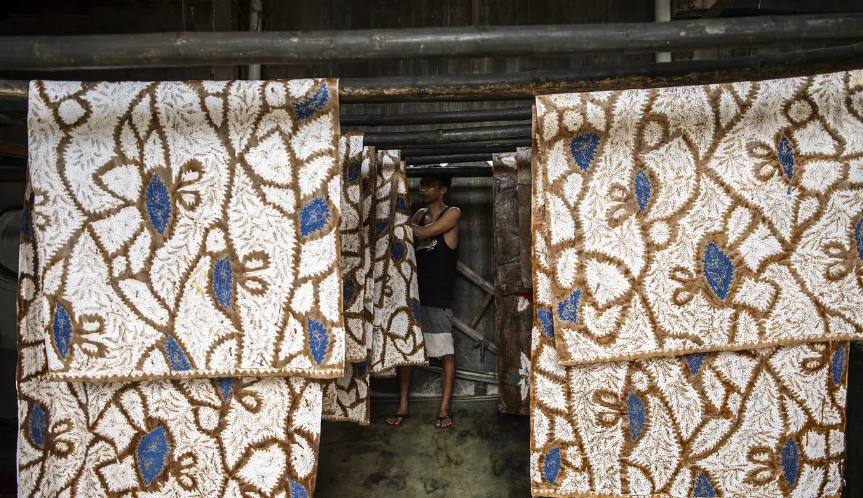 Seorang pekerja menjemur batik di pabrik "batik" kain tradisional Indonesia di Sidoarjo, Jawa Timur (12/11/2019). UNESCO menetapkan batik sebagai karya agung lisan dan warisan budaya takbenda kemanusiaan. (AFP Photo/Juni Kriswanto)