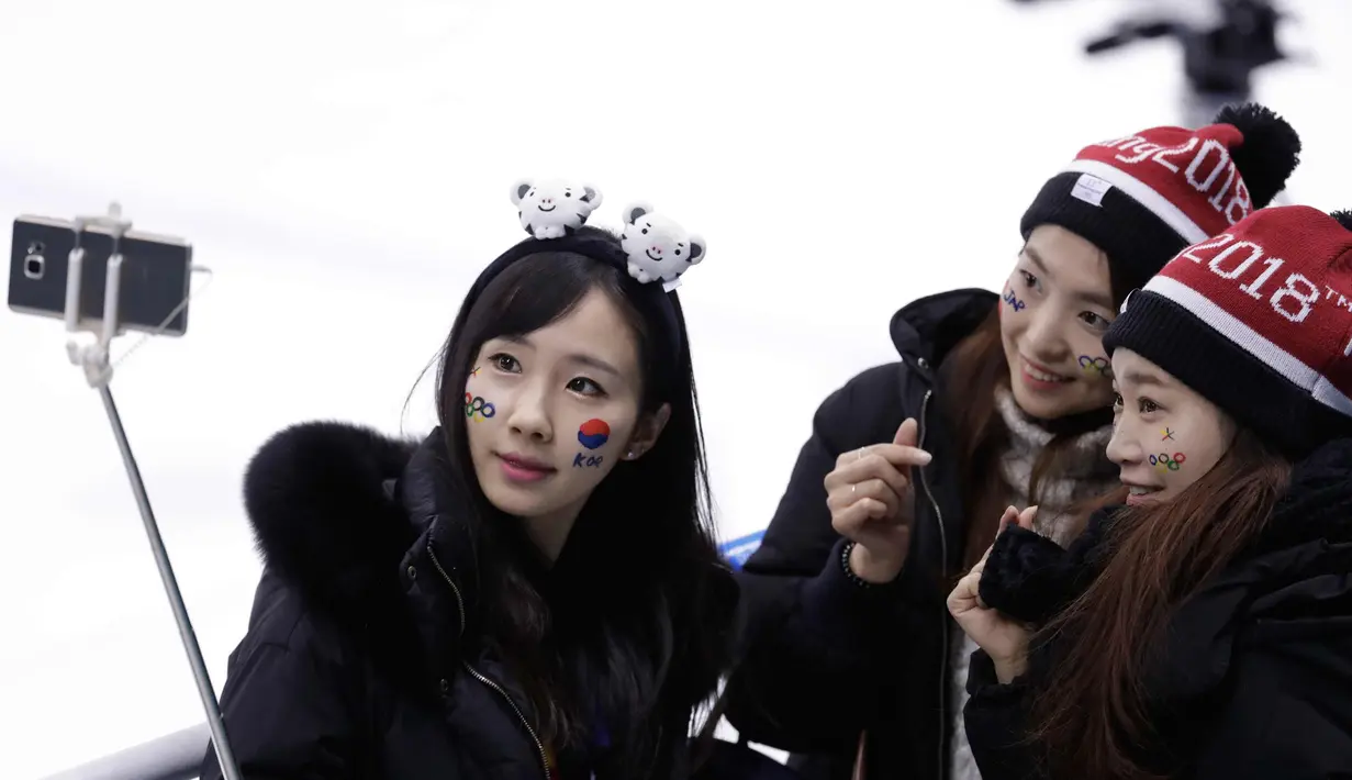 Tiga wanita fans Korea Selatan berselfie sebelum pertandingan babak penyisihan hoki wanita antara Swedia dan gabungan Korea di Olimpiade Musim Dingin 2018 di Gangneung, Korea Selatan, (12/2). (AP Photo / Julio Cortez)
