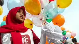 Seorang aktivis perempuan bersiap melepaskan surat pesawat kertas yang diikatkan dengan balon, Jakarta, Minggu (29/5/2016). Surat pesawat kertas tersebut ditujukan untuk Jokowi agar melindungi anak Indonesia dari bahaya rokok. (Liputan6.com/Yoppy Renato) 