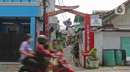 Pengendara motor melintas di depan gapura Kampung Literasi RW 08, Jatipulo, Palmerah, Jakarta Barat, Kamis (30/1/2020). Kampung Literasi ini memiliki 5 kotak berisi beragam buku yang ada di sejumlah titik, berbekal konsep kejujuran disebar di sepanjang kampung. (Liputan6.com/Herman Zakharia)