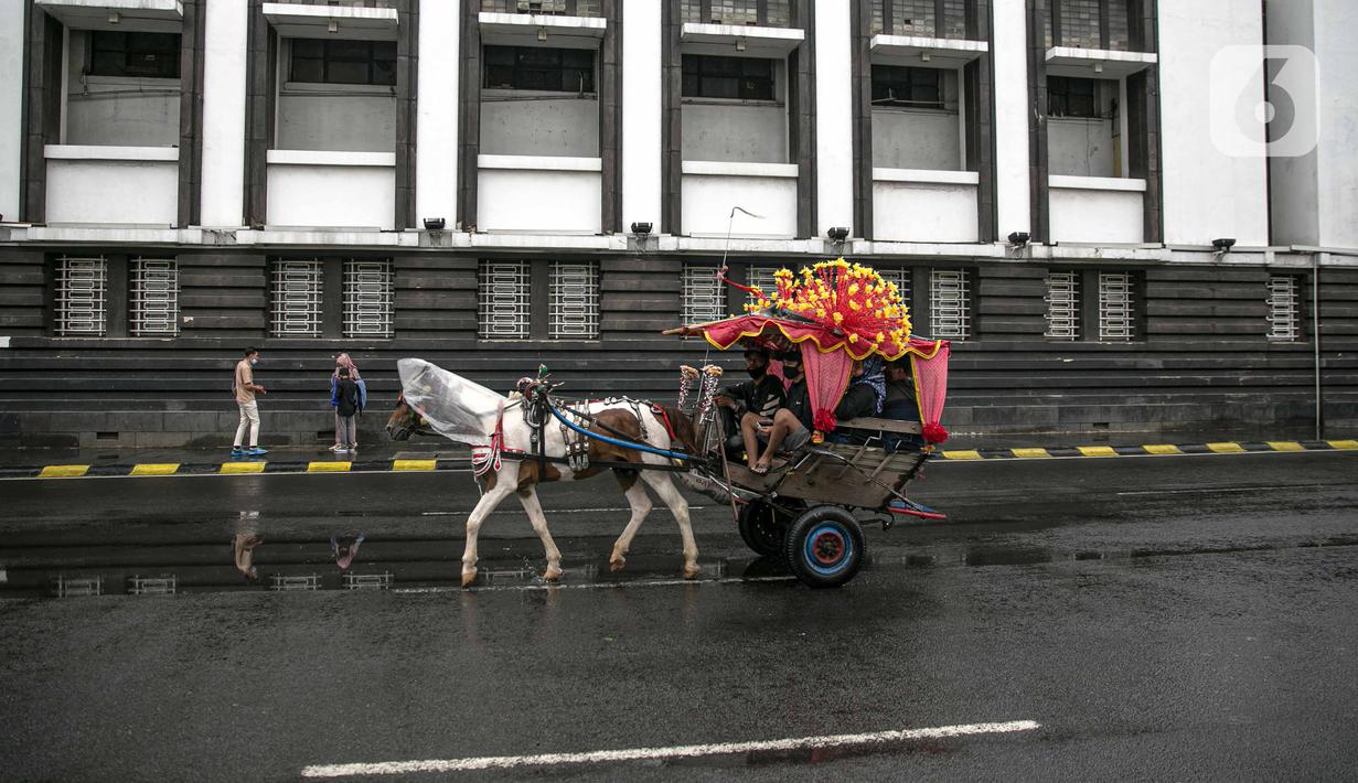 Andong melintas di Kota Tua saat uji coba penerapan zona rendah emisi, Jakarta, Minggu (20/12/2020). Selama penerapan zona rendah emisi, kawasan Kota Tua hanya bisa dilalui pejalan kaki, pesepeda, angkutan umum, dan kendaraan khusus yang lulus uji emisi. (Liputan6.com/Faizal Fanani)