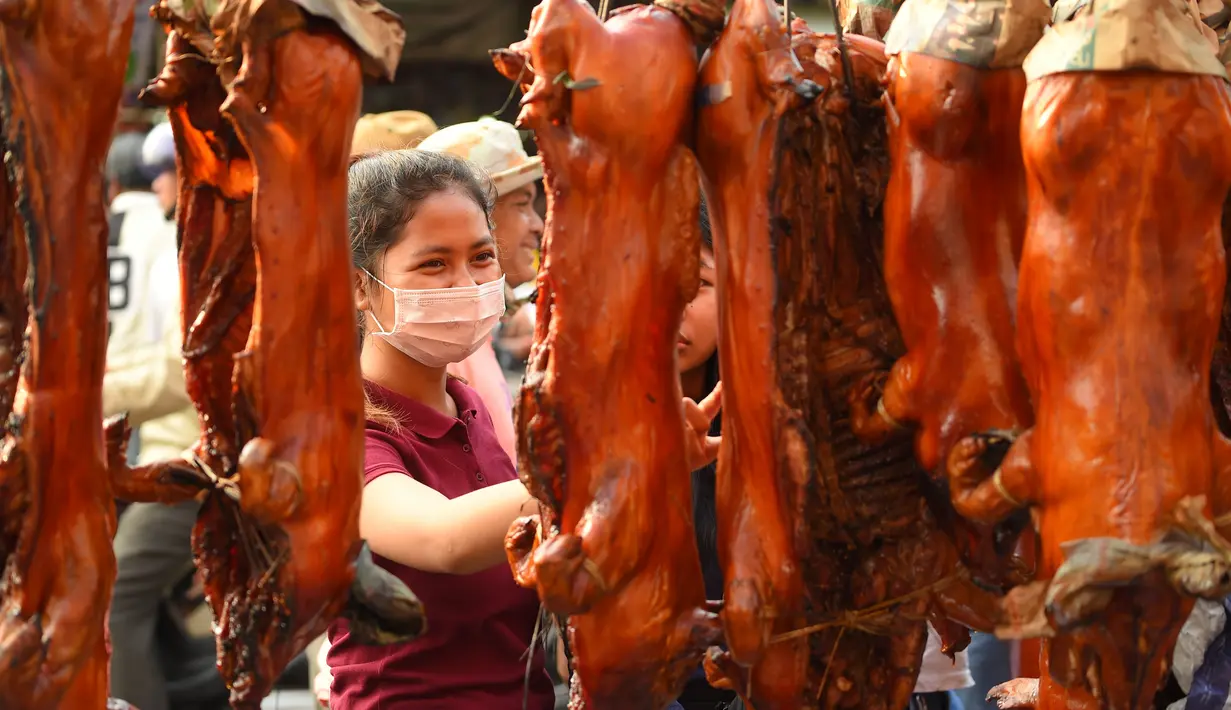 Seorang wanita melihat babi panggang di pasar di Phnom Penh, Kamboja (4/2). Menyambut Tahun Baru Imlek, warga Kamboja mempersiapkan daging babi panggang untuk sajian makan. (AFP Photo/Tang Chhin Sothy)