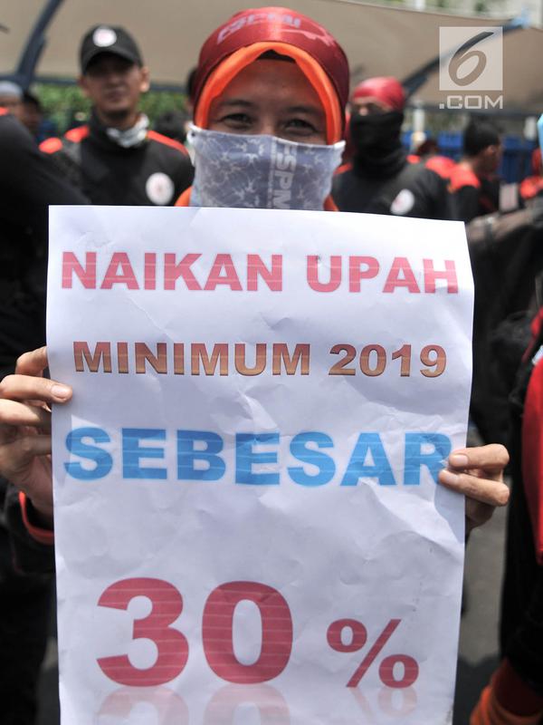 Seorang buruh membawa poster berisi tuntutan kenaikan upah sebesar 30 persen saat menggelar unjuk rasa di depan Gedung Ketenagakerjaan, Jakarta, Rabu (24/10). (Merdeka.com/Iqbal S. Nugroho)