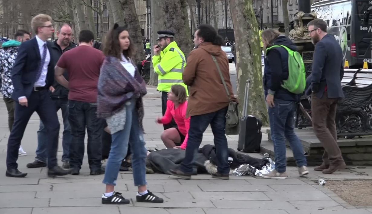 Seorang wanita tergeletak setelah menjadi korban serangan teror di dekat gedung Parlemen Inggris, London, Rabu (22/3). Pelaku ditembak mati oleh anggota polisi lainnya yang berada di gedung parlemen setelah sempat menikam seorang anggota polisi (AP Photo)
