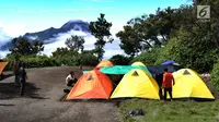 Pendaki mendirikan tenda dengan pemandangan Gunung Merapi dari atas Gunung Merbabu di Selo, Jawa Tengah, Sabtu (2/2/2019). Aktivitas Gunung Merapi dalam beberapa hari terakhir masih tinggi dan masih berada di level 2 atau waspada. (Merdeka/Arie Basuki)