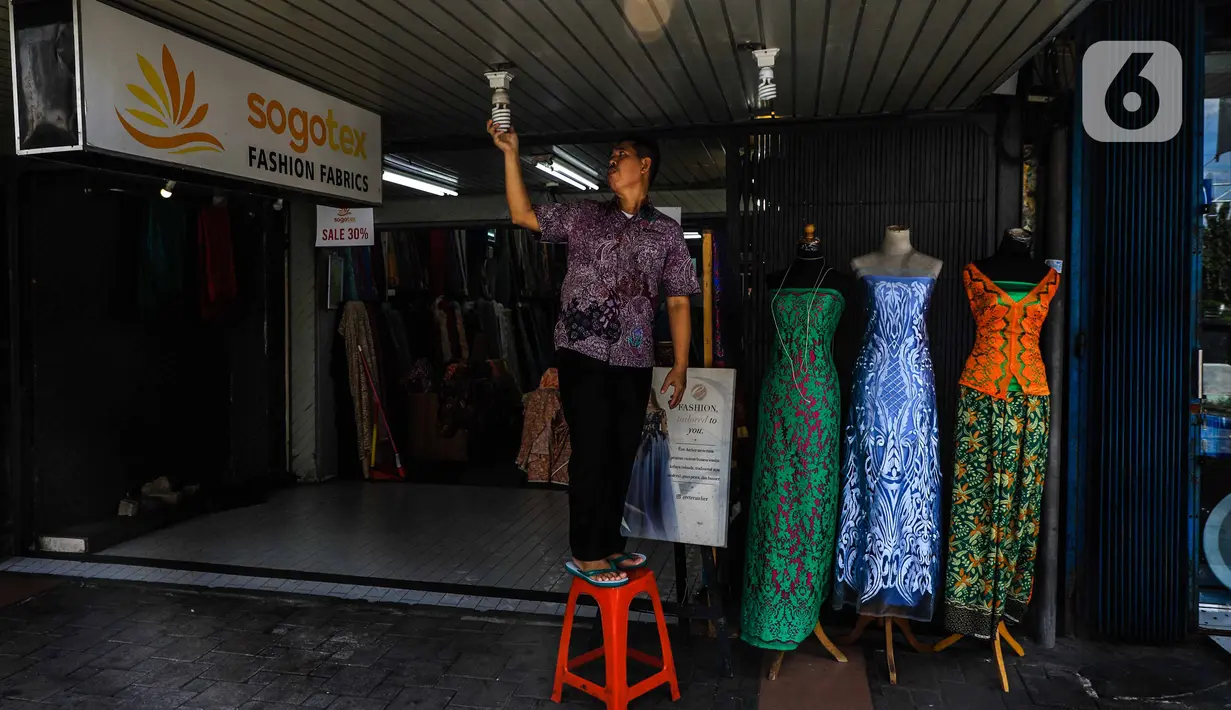 Seorang pria memperbaiki lampu di sebuah toko kawasan perdagangan Pasar Baru, Jakarta, Jumat (3/4/2020). Sebagian pemilik toko di Pasar Baru memilih menutup usahanya sementara waktu untuk mengantisipasi meluasnya penyebaran virus corona COVID-19. (Liputan6.com/Faizal Fanani)