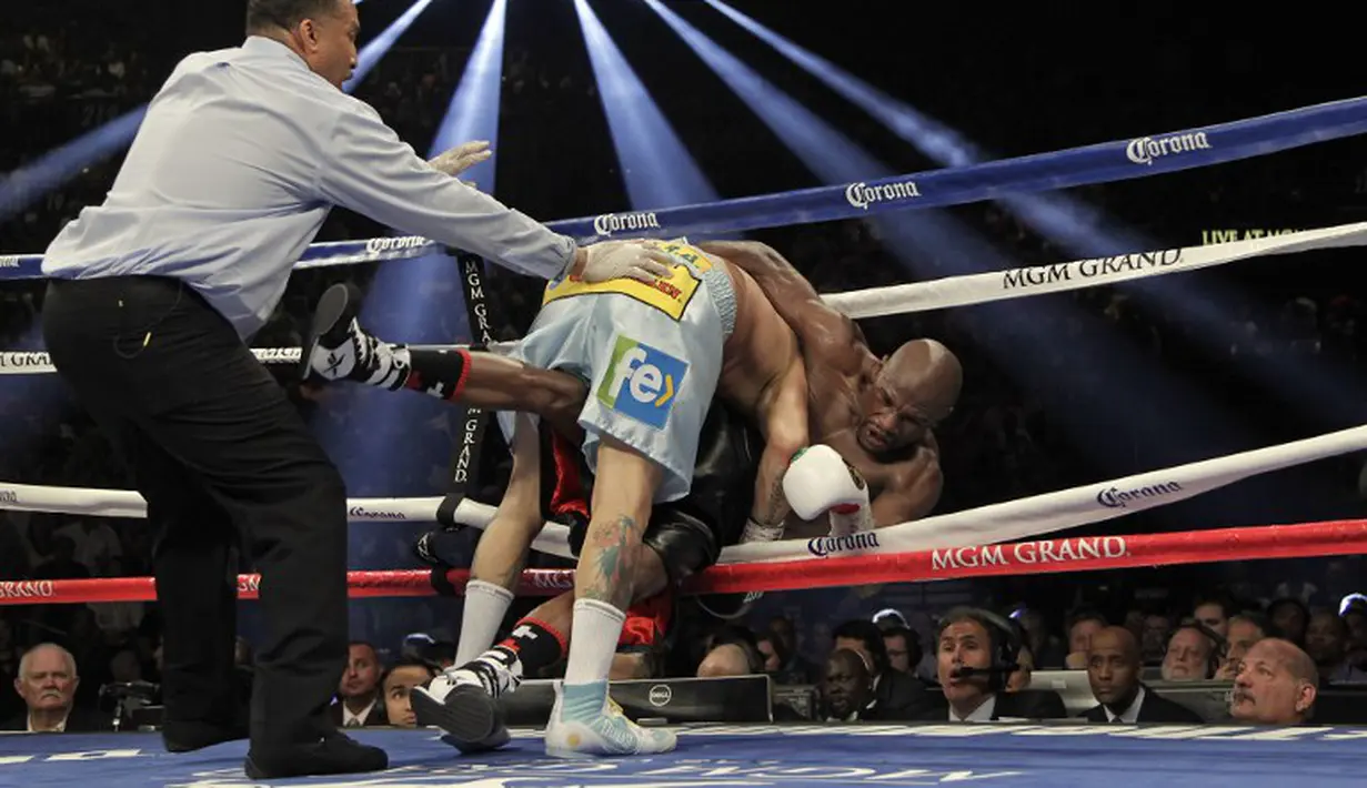  Floyd Mayweather Jr. di dorong ke tali ring oleh Marcos Maidana saat bertarung memperebutkan gelar juara dunia kelas Welter Super WBA. 3 Mei 2014.(AFP)