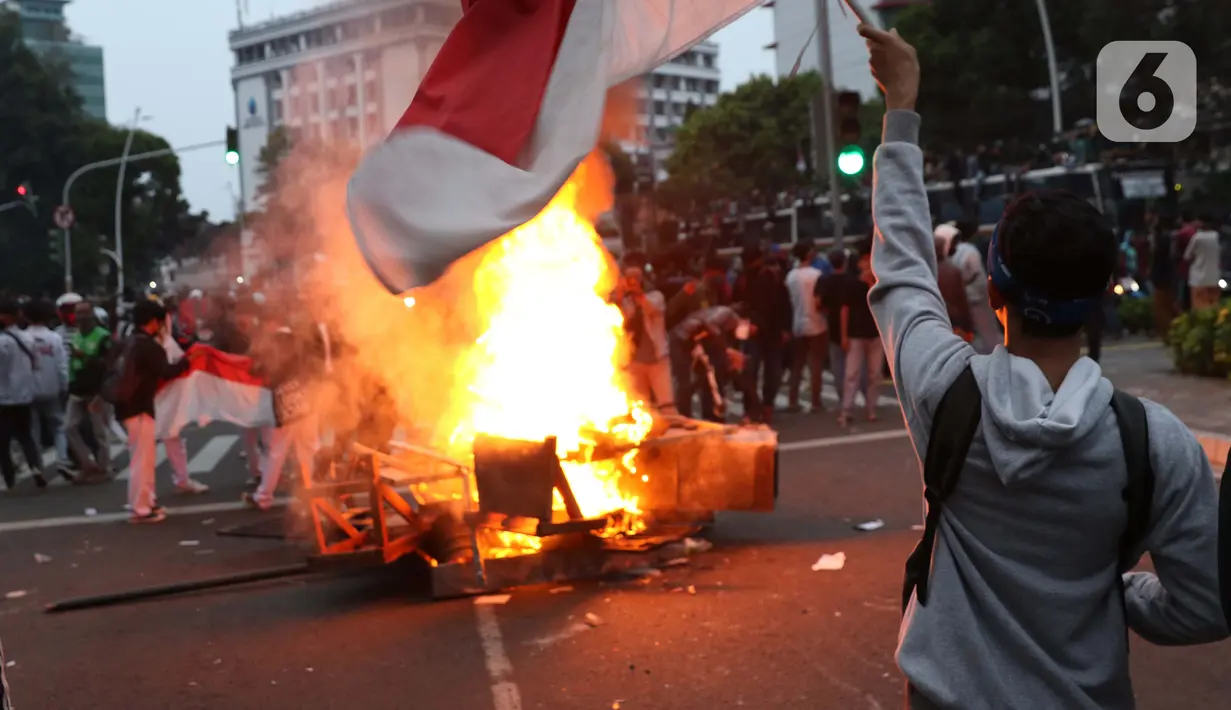 Seorang anak muda mengibarkan bendera Merah Putih di kawasan Gondangdia, Jakarta, Kamis (8/10/2020). Aksi anarkis massa dilakukan saat berunjuk rasa menentang disahkan Omnibus Law UU Cipta Kerja. (Liputan6.com/Helmi Fithriansyah)