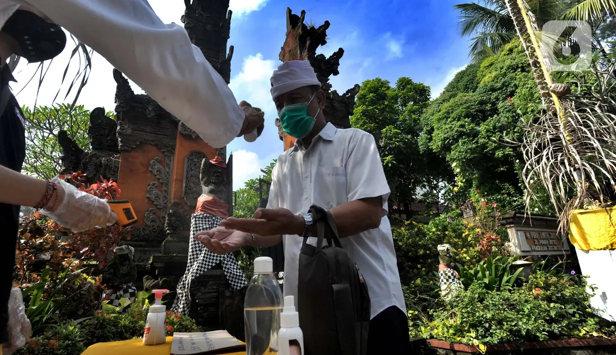 Petugas memberikan cairan hand sanitizer kepada pengurus Pura Amerta Jati menjelang persiapan Hari Raya Nyepi Saka 1942 di Cinere, Depok, Selasa (24/3/2020). Rangkaian Nyepi di sejumlah pura hanya akan dilakukan oleh panitia dalam jumlah terbatas untuk mencegah Covid-19. (merdeka.com/Arie Basuki)