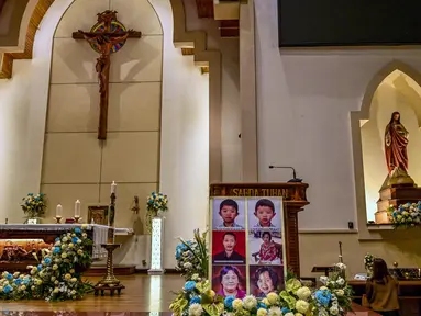 Potret para korban bom bunuh diri terlihat saat orang-orang menghadiri upacara peringatan di Gereja Katolik Santa Maria, Surabaya, Jawa Timur, pada 13 Mei 2025. (Juni KRISWANTO/AFP)