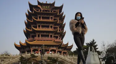 Seorang perempuan bermasker mengunjungi Menara Bangau Kuning yang ikonik di Wuhan di provinsi Hubei, China, Jumat (15/1/2021). Selain masker, orang-orang menjalani kehidupan sehari-hari mereka seperti sebelumnya di Wuhan, tempat pertama kali virus corona COVID-19 terdeteksi. (AP Photo/Ng Han Guan)