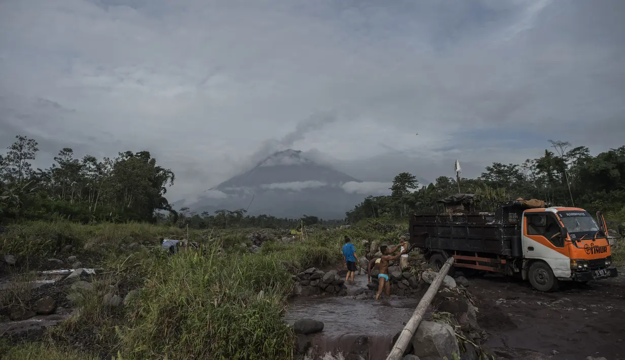 Gunung Semeru menjulang di atas desa Lumajang, Jawa Timur, setelah meletus sehari sebelumnya, Minggu (17/1/2021). Gunung Semeru kembali erupsi dan mengeluarkan awan panas guguran sejauh 4,5 kilometer pada Sabtu (16/1). (Juni Kriswanto / AFP)