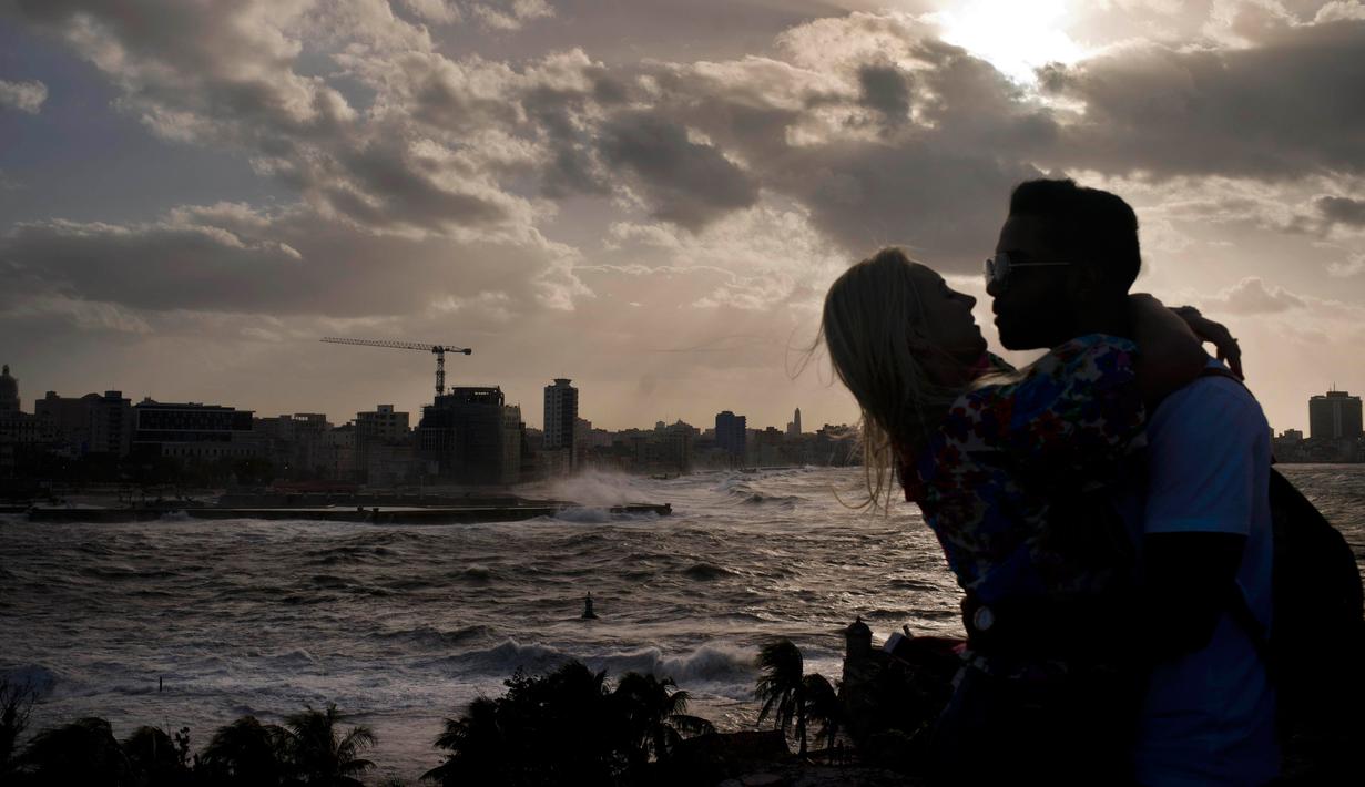 Suami istri berpelukan saaat ombak besar terlihat di laut Malecon di Havana, Kuba (21/12). Letak kota yang berdiri pada tahun 1515 ini relatif strategis. (AP Photo / Ramon Espinosa)