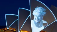 Layar Opera House, landmark ikonik Australia, menyala dengan potret Ratu Elizebeth II di Sydney, Jumat (9/9/2022). Ratu Elizabeth II meninggal dunia pada Kamis 8 September 2022 setelah 70 tahun bertahta. Ia mengembuskan napas terakhirnya di usia 96 tahun. (Photo by Robert WALLACE / AFP)