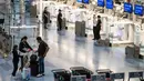 Penumpang menunggu di dekat konter check-in yang kosong di Terminal Internasional Bandara Haneda setelah penerbangan dibatalkan atau ditunda karena badai tropis Jangmi di Tokyo, Jepang, Rabu 3 Juni 2026. (Andrew CAALLERO-REYNOLDS/AFP)