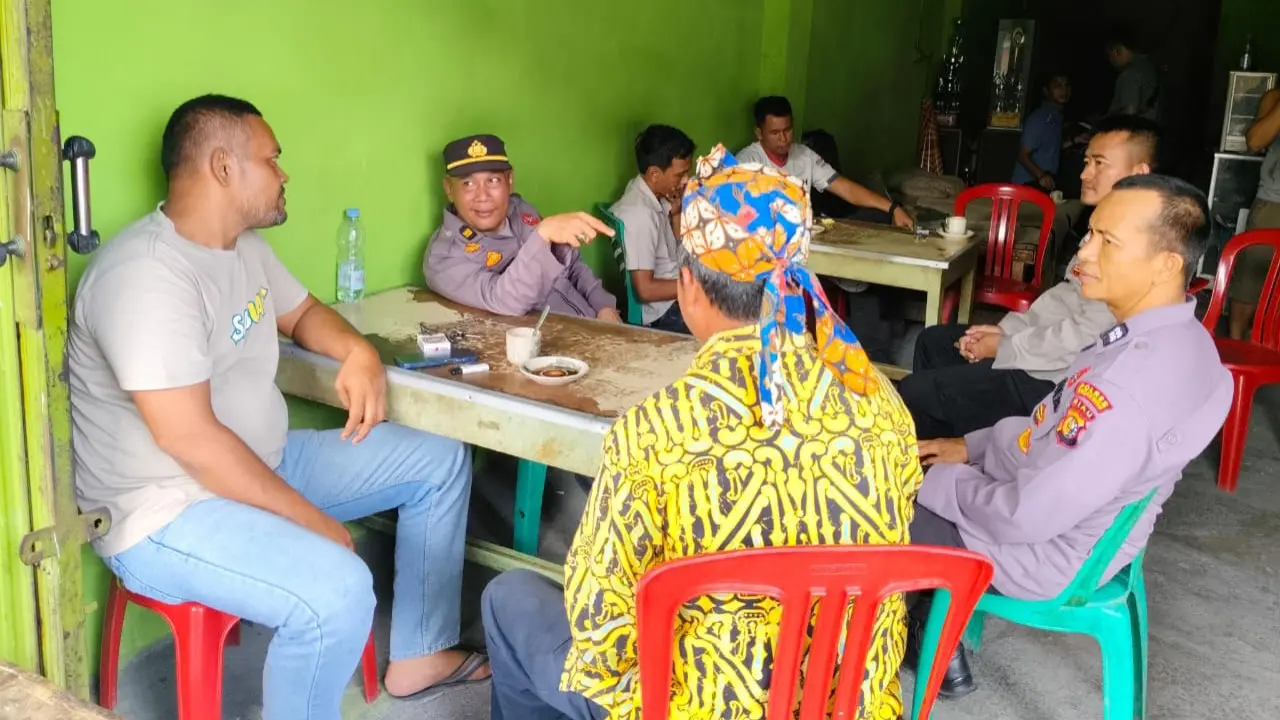 Personel Polres Rokan Hulu berdiskusi bahas Pilkada 2024 di warung kopi bersama warga.