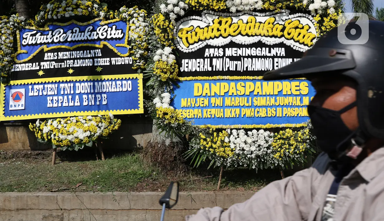Warga melintas di depan karangan bunga tanda duka cita atas meninggalnya mantan KSAD Jenderal TNI (Purn) Pramono Edhie Wibowo di kawasan Puri Cikeas, Kab Bogor, Jabar, Minggu (14/6/2020). Pramono Edhie Wibowo wafat di usia 65 tahun akibat serangan jantung. (Liputan6.com/Helmi Fithriansyah)