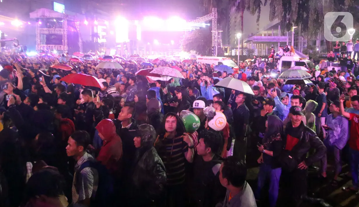 Warga berkerumun menikmati salah satu panggung hiburan di Bundaran Hotel Indonesia, Jakarta, Selasa (31/12/2019). Meski Jakarta diguyur hujan sejak Selasa (31/12) sore, warga tetap antusias melewati malam pergantian tahun 2019 menuju 2020 di kawasan Bundaran HI Jakarta. (Liputan6.com/Angga Yuniar)