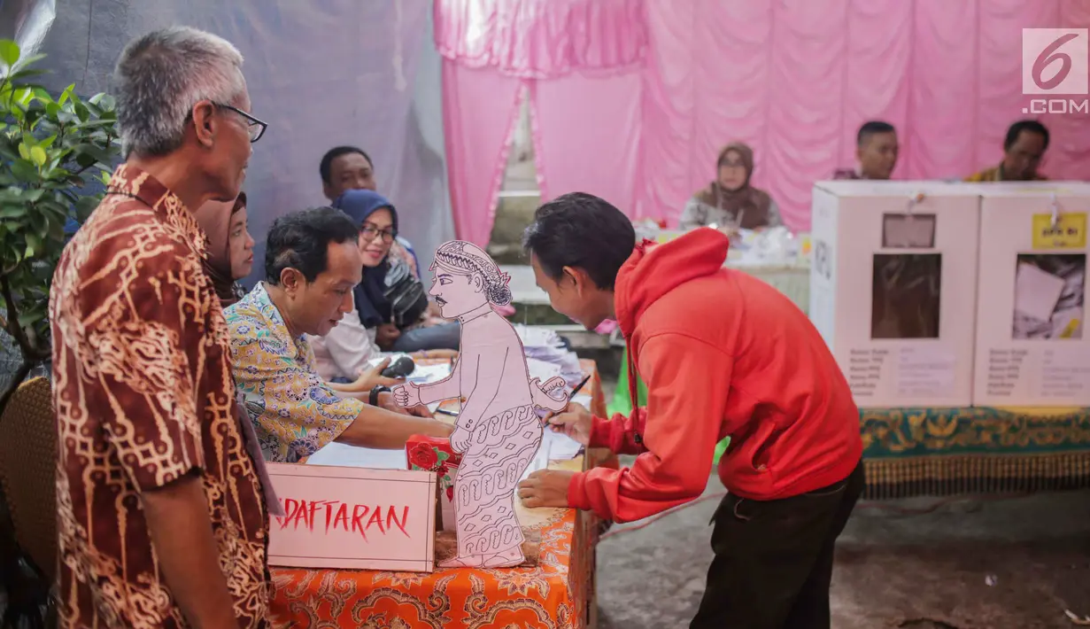 Calon pemilih mendaftar ke petugas Kelompok Penyelenggara Pemungutan Suara (KPPS) saat akan mencoblos di TPS 45 Kebon Pala, Jakarta, Rabu (17/5). TPS tersebut mengambil tema suasana pernikahan adat Jawa untuk menarik minat pemilih dan menekan angka golput. (Liputan6.com/Faizal Fanani)