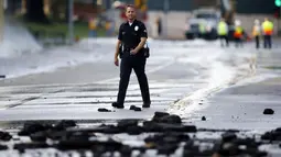 Seorang anggota kepolisian berjalan melintasi pecahan aspal akibat rusaknya pipa utama saluran air bawah tanah di sekitar Sunset Boulevard di bagian Westwood Los Angeles, (29/7/2014). (REUTERS/Danny Moloshok)