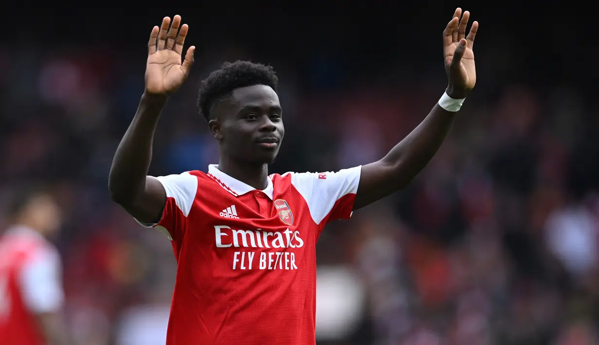 Gelandang Arsenal, Bukayo Saka memberi penghormatan kepada fans usai berakhirnya laga menghadapi Crystal Palace pada laga Liga Inggris 2022/2023 di Emirates Stadium, London (19/3/2023). Serupa dengan Gabriel Martinelli, Bukayo Saka juga tak pernah absen membela Arsenal dalam 33 laga di Liga Inggris musim 2022/2023. Ketajamannya sebagai pencetak gol dan assist sama baiknya, dengan koleksi 13 gol dan 11 assist. (AFP/Justin Tallis)