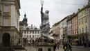Pejalan kaki berjalan melewati patung yang dibungkus dengan plastik pelindung di sebelah Katedral Latin di Lviv, 5 Maret 2022. Warga kota Lviv membungkus semua patung untuk melindungi warisan sejarahnya dari kerusakan akibat serangan di tengah konflik Rusia-Ukraina. (Daniel LEAL/AFP)