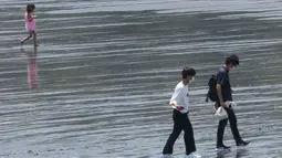 Orang-orang berjalan di pantai Katase-kaigan di Fujisawa, prefektur Kanagawa, dekat Tokyo, Senin (8/6/2020). Jepang mengangkat keadaan darurat coronavirus-nya, mengakhiri pembatasan secara nasional ketika bisnis mulai dibuka kembali. (AP Photo/Koji Sasahara)