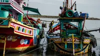Dua nelayan membawa hasil tangkapannya dari perahu saat tiba di sebuah tempat pelelangan ikan di Brondong, Lamongan, Jawa Timur, Senin (13/3). (AFP Photo/Juni Kriswanto)