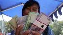 Warga menunjukan uang pecahan Rupiah di layanan mobil kas keliling Bank Indonesia di Lapangan IRTI, Monas, Jakarta, Kamis (2/7). Sebanyak 15 bank membuka gerai penukaran uang pecahan hingga 15 Juli mendatang. (Liputan6com/Helmi Afandi)