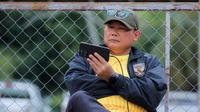 Manajer Timnas Indonesia U-22, Sumardji, tampak serius menyaksikan laga Timnas Vietnam U-22 vs Timnas Malaysia U-22 dari layar handphone. (Bola.com/Bagaskara Lazuardi)