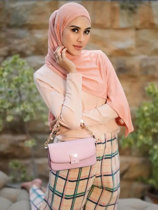 Melihat gaya manis Syahnaz Sadiqah pakai warna pastel. Ia memadukan atasan kaus lengan panjang berwarna pink yang serasi dengan hijabnya, celana bermotif kotak-kotak bernuansa senada, dan tas pink yang serasi. [Foto: Instagram/syahnazs]