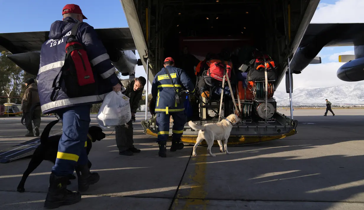 Petugas pemadam kebakaran Yunani dengan anjing menaiki pesawat militer di Pangkalan Angkatan Udara Elefsina, di barat Athena, Yunani, Senin (6/2/2023). Yunani mengumumkan akan mengirimkan tim yang terdiri dari 21 penyelamat, dua anjing penyelamat, dan kendaraan penyelamat khusus, bersama dengan seorang insinyur struktur, lima dokter dan ahli perencanaan seismik, semuanya bepergian dengan pesawat angkut militer. (AP Photo/Thanassis Stavrakis)