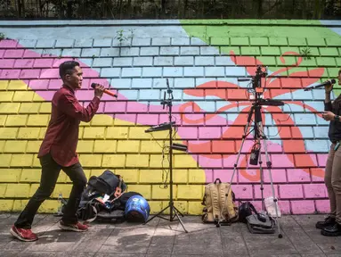 Para penyanyi dalam jaringan (daring/online) menggunakan dinding berwarna-warni sebagai latar belakang tampil untuk menarik penonton agar memberikan donasi digital selama siaran langsung mereka di situs media sosial, Bandung, Jawa Barat, pada Jumat 8 Mei 2026. Fenomena penyanyi yang tampil melalui siaran langsung melalui internet (live streaming) di situs media sosial kian marak. (Timur Matahari/AFP)