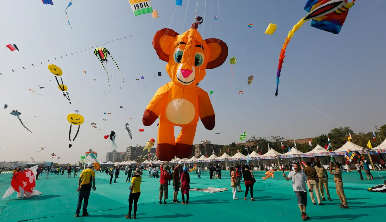 Warga India menonton festival layang-layang Internasional di Ahmadabad, India (7/1). Dalam festival ini layang-layang dari berbagai negara menghiasi langit Ahmadabad, India. (AP Photo/Ajit Solanki)
