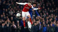 Pemain Arsenal, Shkodran Mustafi dan pemain Chelsea, Willian melompat untuk berebut bola pada laga semifinal pertama Piala Liga Inggris di Stadion Stamford Bridge, Rabu (10/1). Chelsea dan Arsenal bermain imbang tanpa gol. (AP/Kirsty Wigglesworth)