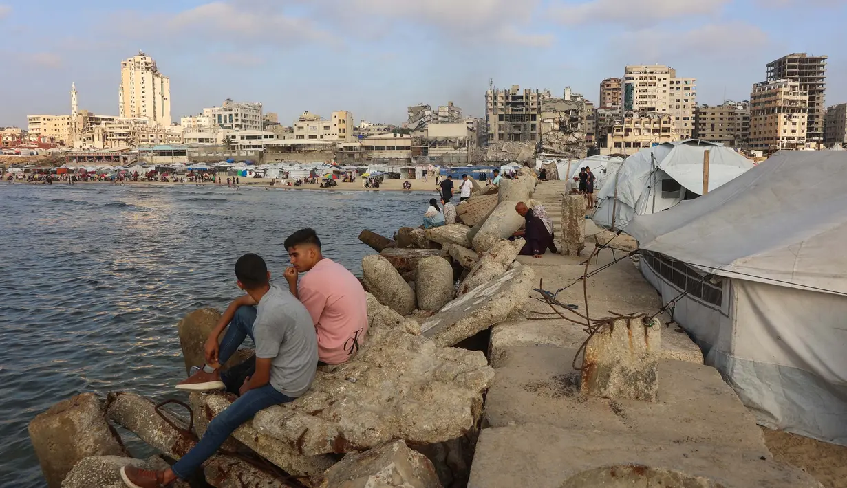 Warga Palestina yang mengungsi memanfaatkan pantai tersebut sebagai tempat untuk menghibur diri mereka di tengah berlangsungnya perang antara Israel dan milisi Hamas. (Omar AL-QATTAA/AFP)