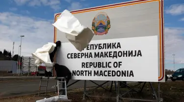 Pekerja mengganti papan nama negara menjadi Republik Makedonia Utara di perbatasan antara negara itu dengan Yunani, dekat Gevgelija, Rabu (13/2). Kini sah sudah Republik Makedonia menyandang nama baru yaitu Republik Makedonia Utara. (AP/Boris Grdanoski)