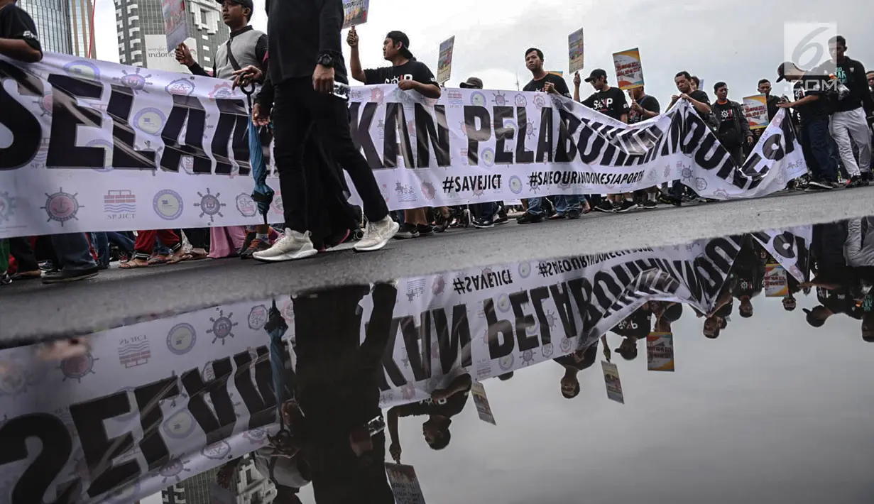 Massa Serikat Pekerja Container (SPC) melewati genangan air saat menggelar karnaval pelabuhan di area CFD, Jalan Thamrin, Jakarta, Minggu (17/2). Massa menolak liberalisasi pengelolaan Pelabuhan Tanjung Priok oleh vendor asing. (Liputan6.com/HO/Mico)