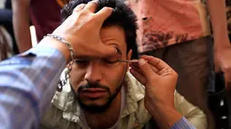 Seorang pria Yaman saat kelopak matanya dirias dengan kosmetik tradisional kohl di Masjid Agung, kota tua Sanaa pada 9 mei 2019. Bagi muslim Yaman, pemakaian kohl diyakini mampu membersihkan dan melindungi mata dari penyakit ini sudah menjadi tradisi setiap bulan Ramadan. (MOHAMMED HUWAIS/AFP)