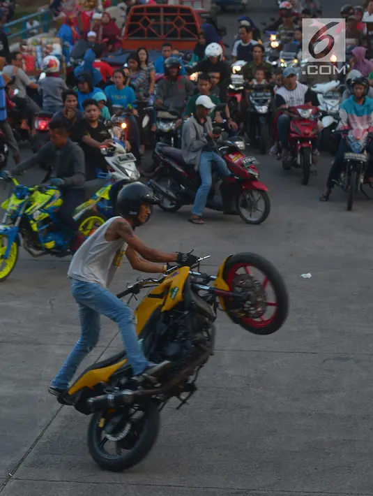 Warga menyaksikan atraksi para freestyle dengan motor di kawasan Kanal Banjir Timur, Jakarta, Selasa (29/5). Sekelompok pemuda di kawasan itu memanfaatkan waktu menunggu berbuka dengan melakukan atraksi freestyle yang mendebarkan (Merdeka.com/Imam Buhori)
